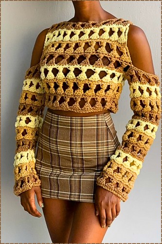 Finished crochet cold shoulder top in brown and yellow granny stitch with long sleeves and open shoulder cutouts worn with a plaid mini skirt